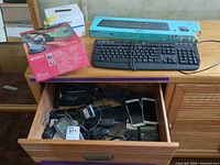 Overview showing Logitech wired keyboard, Logitech MK235 box, Sony headphone box, OrCam box and drawer with phones and chargers