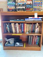 Full view of medium oak veneer bookcase with three shelves and contents for scale