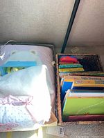 Overall view of basket of books next to box with blanket and rattles