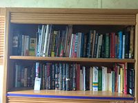 Two shelves filled edge-to-edge with mixed hardcovers, paperbacks and spiral books