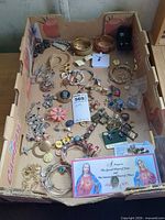 Overall lot view in cardboard tray showing variety of jewelry pieces