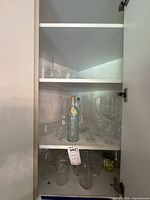 Cabinet view showing aqua bottle, tumblers, flutes, additional glasses