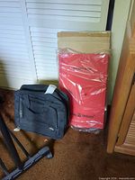 Black Olympia suitcase and boxed red Total Trolley cart photographed together