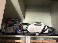 Vacuum with hose and wand plus bag packs on shelf