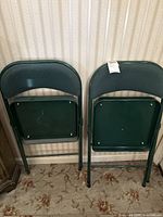 Front view of both folded chairs showing green metal frames and upholstery