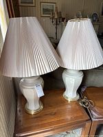 pair of white ceramic lamps with shades on wooden table