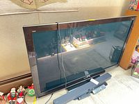 Front view of Panasonic TV, Sony sound bar, and remotes