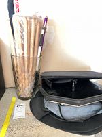 Bundle of drumsticks and mallets in glass, carrying bag beside