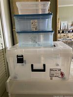 Stack of assorted clear Sterilite bins showing variety of sizes and lids