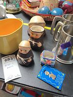 Overall view of two brown/cream monk figurines with other items