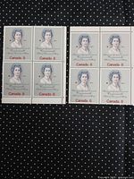 Two blocks of four 1973 Canada 8¢ Queen Elizabeth II stamps on dark polka-dot background