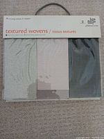 Front of JF Fabrics Textured Wovens sample book with three visible swatches