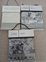 Three fabric swatch booklets laid out showing covers and hanging straps