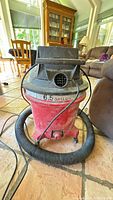 Front view of red/black 6.5-gallon shop vacuum with hose and cord visible