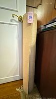 Full view of beige woven fabric roll standing vertically