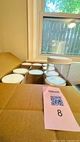 Box containing multiple clear jars with white lids