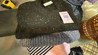 Stack of three folded sweaters showing colors and textures