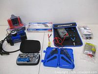 All items laid out including air compressor, screwdriver sets, electrical kit, knife set and hex keys