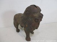 Front angled view of cast iron lion bank showing coin slot on head
