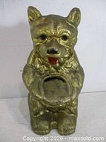 Front view of gold painted cast iron teddy bear bank showing coin slot and facial details