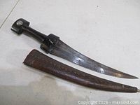 Dagger beside scabbard showing full length and curvature
