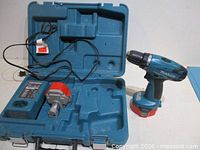 Open carry case showing charger, two batteries and drill