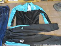 Adidas Real Madrid jacket laid flat beside Nike Brazil pants and Adidas pants