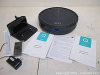 Complete lot overview showing robotic vacuum, charging dock, power adapter, accessory piece, and two manuals