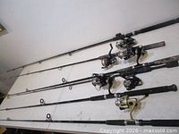 Six fishing rods with reels laid on table