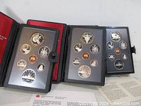 Three cased Royal Canadian Mint double dollar sets opened to display coins