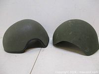 Two green Kevlar helmet shells side by side