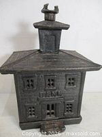 Front three-quarter view of cast iron bank building coin bank