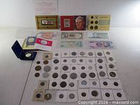 Overall lot layout showing medals, stamp booklets, coin set, loose and flipped coins, banknotes