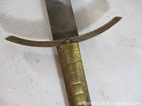 Close-up of brass grip and downturned crossguard on steel blade