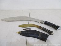 Two kukris, small knife, sheath displayed