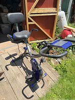 Full side view of FitNation stationary exercise bike showing seat with backrest, handlebars, pedals, blue accents