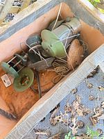 Box containing assorted green and silver propane lantern heads, bases and parts