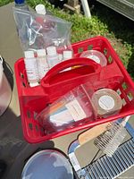 Red tote with fragrance bottles, colorants, molds, tape; soap cutter and scale visible below