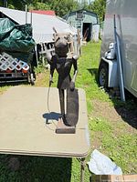 Full view of tin suit of armor statue on table outdoors