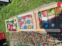 Two boxed ornament sets and open Woolworth box showing glass balls plus bead garlands
