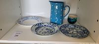 Shelf view showing blue polka-dot jug, three blue-and-white dishes, small blue-green bowl
