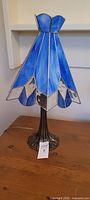 Full view of blue and clear stained glass lamp on table
