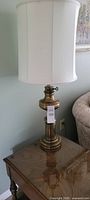 Full view of brass lamp with shade on side table