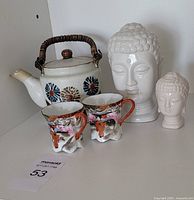 Group shot of two Buddha heads, teapot and two Japan cups