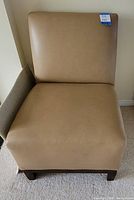 Front view of caramel faux-leather chair showing full seat, back and wooden legs