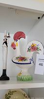 Ceramic rooster and metal chef figurines on shelf