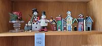 Full shelf view showing snowmen, candleholder, child figurines, village buildings