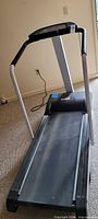 Full view of treadmill showing running deck, frame and power cord