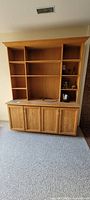 Full view of oak wall unit showing upper shelves and lower cupboards