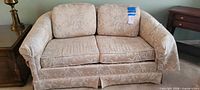 Front view of the light taupe floral jacquard loveseat showing overall style and condition